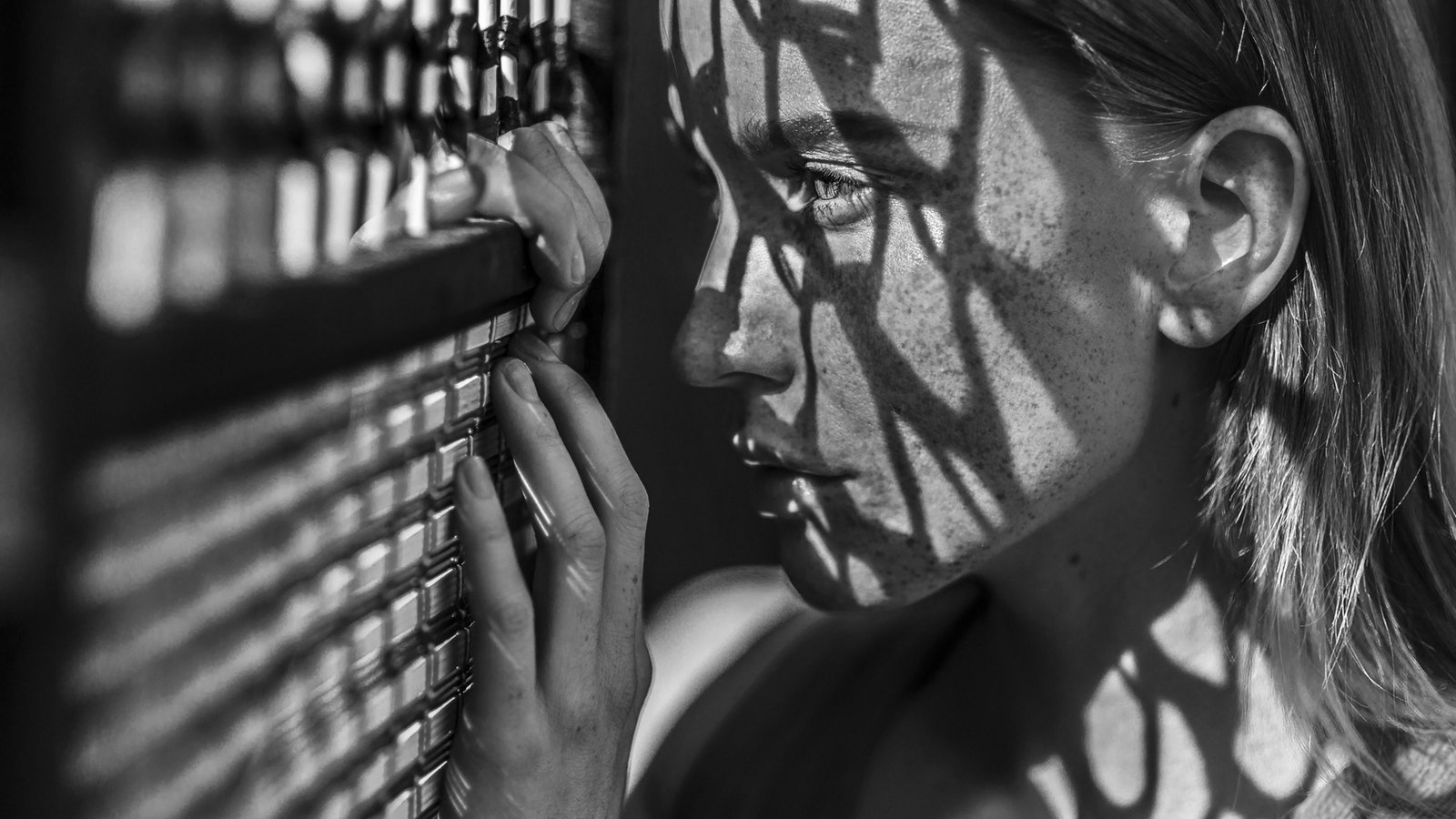 Eine Frau schaut durch einen engmaschigen Zaun, auf ihr Gesicht fallen die Schatten der Maschen. | Bildquelle: picture alliance / Bildagentur-online/Blend Images/Ivan Ozerov" Eine Frau schaut durch einen engmaschigen Zaun, auf ihr Gesicht fallen die Schatten der Maschen.