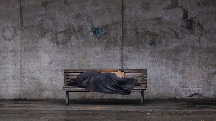 schlafender Obdachloser auf einer Bank in Berlin.