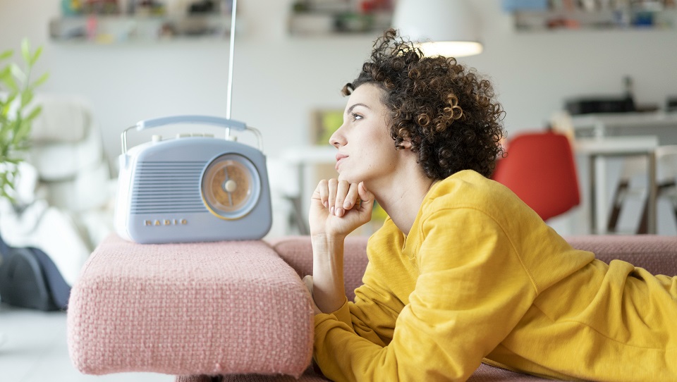 Woman lying on couch listening to music with portable radio