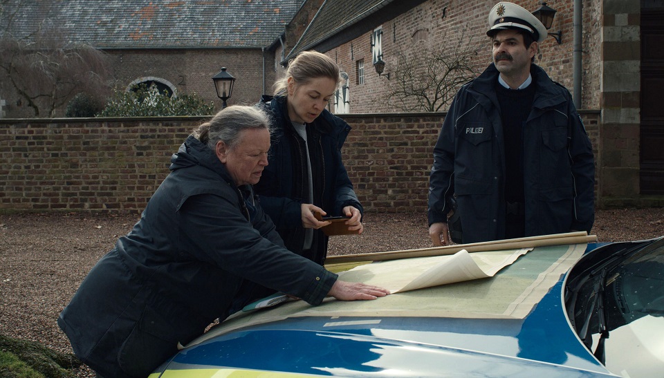 Alfons Tenhagen (Andreas Döhler rechts) Saskia Harder (Valery Tschepanowa mittig) und Edith Telaar (Ursula Werner links) schauen sich eine Karte über den Wasserstand des Moors an. | Bildquelle: WDR/Panossian/Petrolio Film Alfons Tenhagen (Andreas Döhler rechts) Saskia Harder (Valery Tschepanowa mittig) und Edith Telaar (Ursula Werner links) schauen sich eine Karte über den Wasserstand des Moors an.