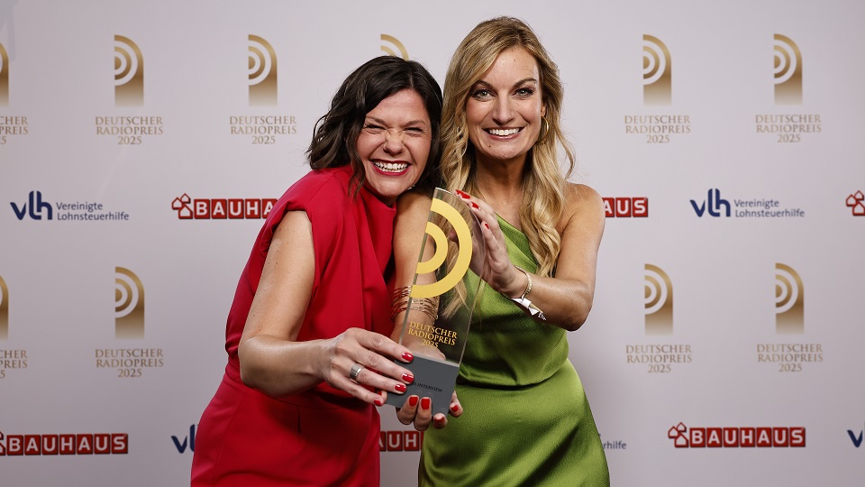 Freddie Schürheck (Mitte) und Judith Biedermann nahmen stellvertretend für das Team den Preis für die Podcast-Folge mit Paracyclerin Maike Hausberger von Laudator Joachim Meyerhoff entgegen.