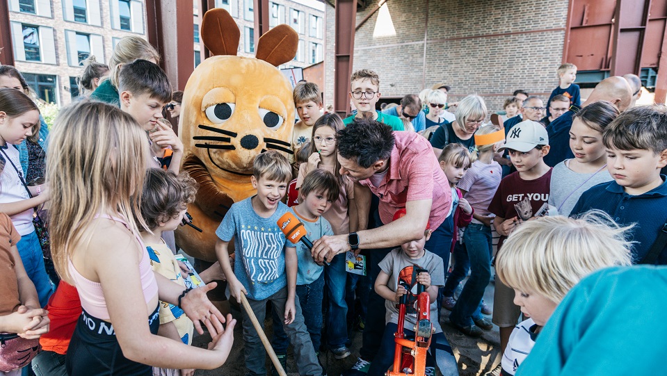 WDR-Moderator André Gatzke zusammen mit der Maus und Kindern in der Zeche Zollverein.