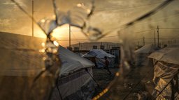 Ein zerschossene Scheibe, dahinter das Flüchtlingscamp Badarash im Nordirak