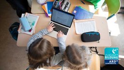 Schüler einer fünften Klasse benutzen im Unterricht einen Laptop