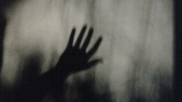 Körnige schwarzweiß Fotografie einer Hand hinter einer milchigen Glasscheibe