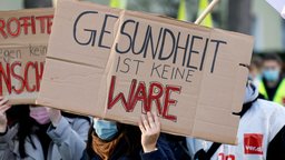 Plakat auf einer Demonstration mit der Aufschrift "Gesundheit ist keine Ware" | Bildquelle: Christoph Hardt/Geisler-Fotopres Plakat auf einer Demonstration mit der Aufschrift "Gesundheit ist keine Ware"