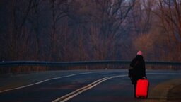 Eine Frau, die vor dem Krieg in der Ukraine geflohen ist, geht mit ihrem Gepäck an der ukrainisch-polnischen Grenze