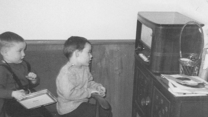 Zwei Kinder sitzen vor einem Radiogerät.