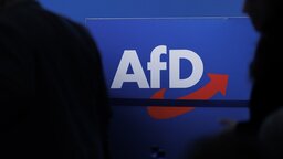 Delegierte gehen vor dem Parteilogo bei dem AfD-Bundesparteitag