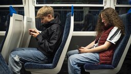 Boy and girl using smart phones sitting in train model