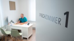 Ein Hausarzt sitzt in einem Sprechzimmer seiner Hausarztpraxis
