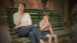 Mutter und Sohn sitzen mit Abstand auf der Bank.